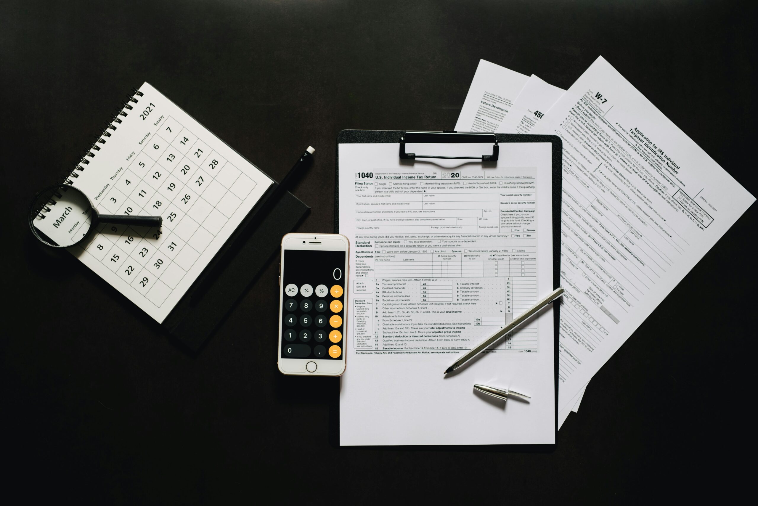 Flat lay of financial tools for tax preparation including forms, calculator, and calendar.
