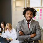 Professional business leader posing confidently in a modern office with team.