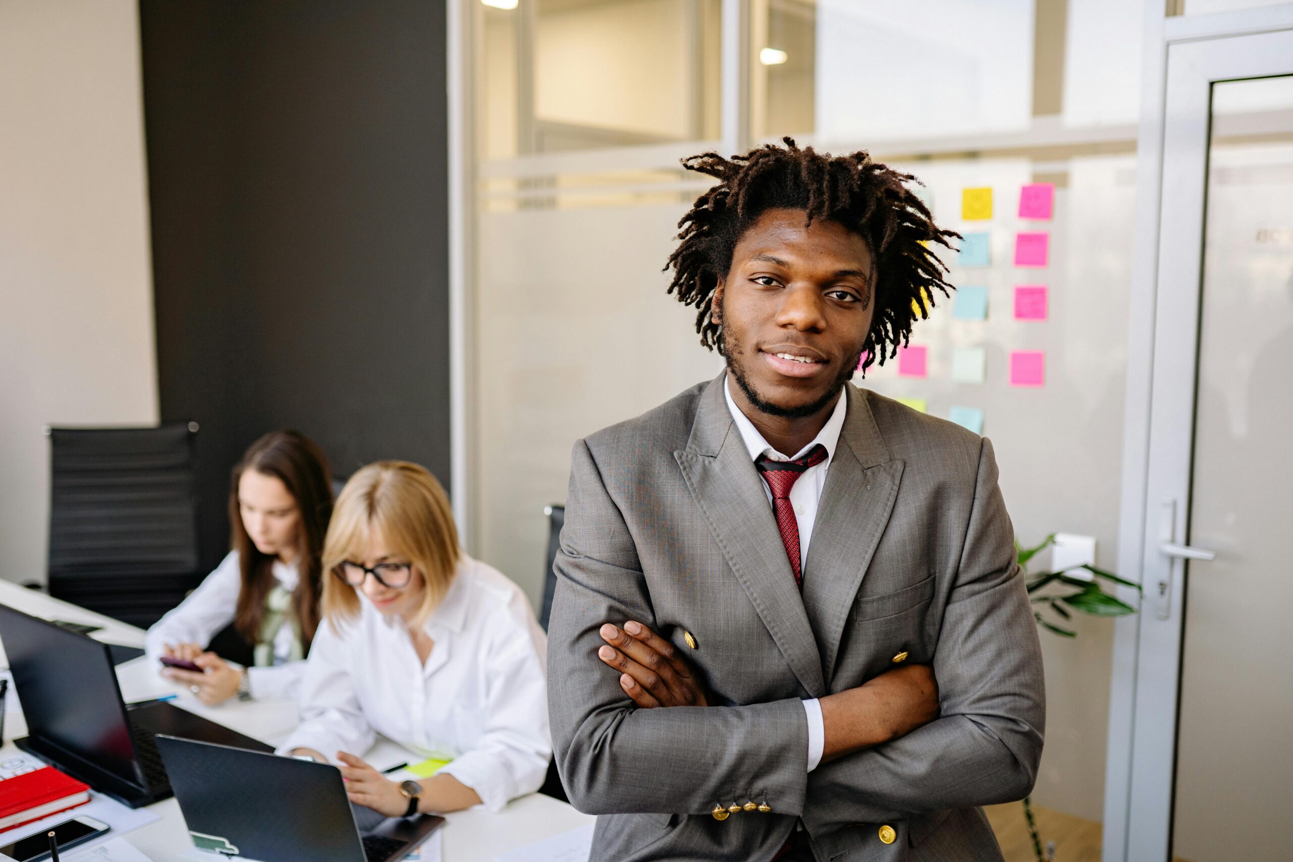 Professional business leader posing confidently in a modern office with team.